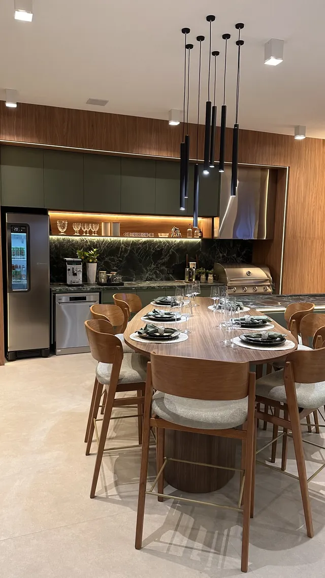 Cozinha gourmet com mesa posta para oito lugares, ilha com banquetas e pendentes, iluminação embutida