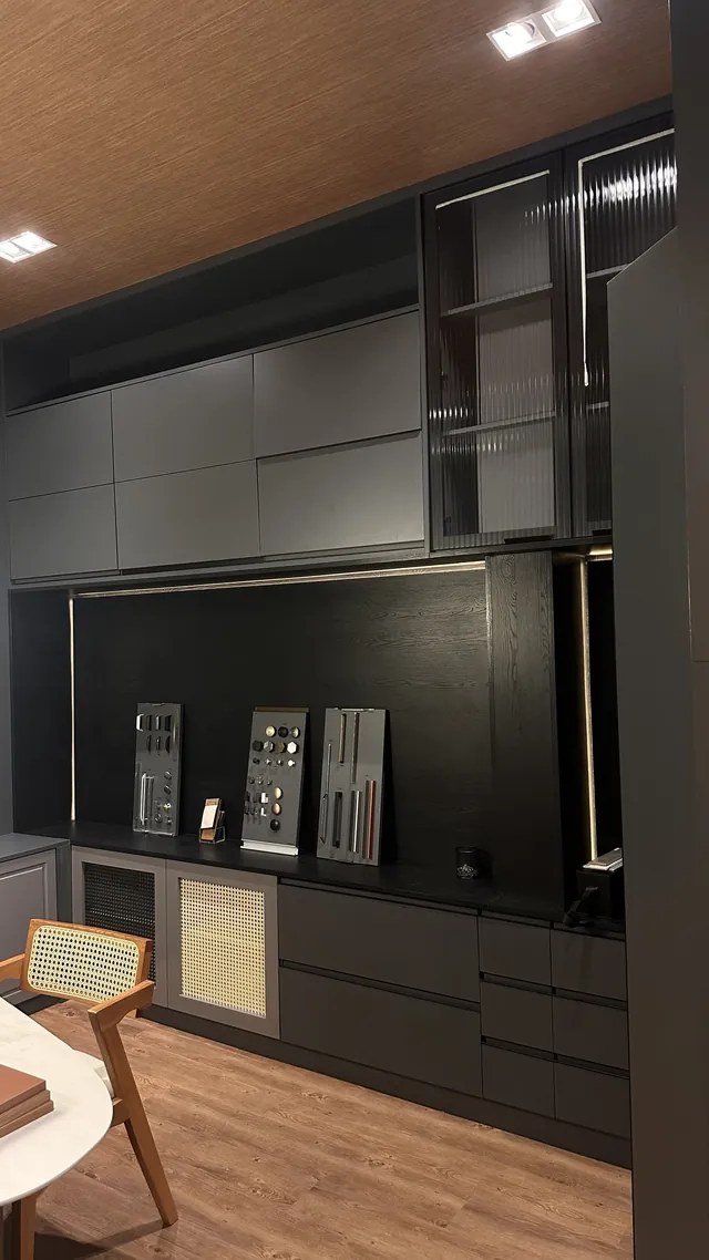 Ambiente do showroom da Smart House com marcenaria preta, nichos iluminados e amostras de materiais
